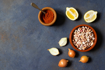 Prebranac ingredients. Balkan baked beans. Serbian, Montenegrin, Bosnian, Croatian and Slovenian cuisine. Uncooked beans, onion, lemon, paprika powder. Dark background. Top view. Space for text
