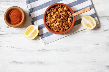 Prebranac. Balkan baked beans. Serbian, Montenegrin, Bosnian, Croatian, Slovenian cuisine. Uncooked beans, onion, lemon, paprika powder. White wooden background. Top view. Space for text