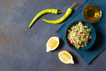 Tabbouleh salad with couscous, parsley, lemon, tomato, olive oil. Levantine vegetarian salad. Lebanese, arabic cuisine. Dark background. Top view. Space for text