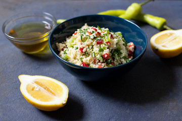 Tabbouleh salad with couscous, parsley, lemon, tomato, olive oil. Levantine vegetarian salad. Lebanese, arabic cuisine. Dark background. Close up view