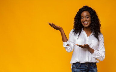 Cute black girl pointing with palms up at empty space
