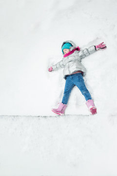 little cheerful girl lies on white snow