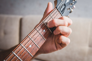 Am7 chord - close-up male Caucasian hand takes a chord on a 6 string guitar