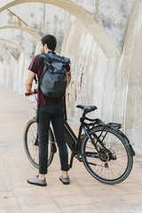 Fototapeta premium Back view of a man standing next to e-bike