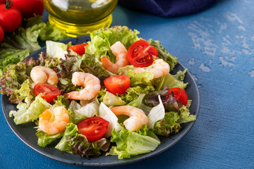 Healthy and diet salad with shrimps, tomatoes and mixed greens on a plate. Copy space