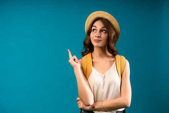 Indoor photo of beautiful young female in white blause isolated on blue background with bag on her back. Solution found.