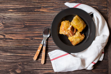 Sarma - traditional dish of Balkan cuisine. Cabbage rolls with meat and rice. Balkan cuisine. Serbian cuisine. Dark wooden background. Top view. Space for text