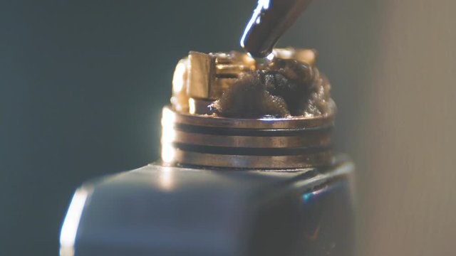 Rebuildable dripping atomizer or RDA for vaping or e-cigarette coil and cotton stripes wetted with e-liquid, modern vape device for quit smoking, macro 4K