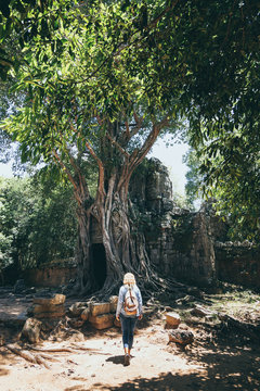 Caucasian blonde woman discovering the ruins of Angkor Wat temple complex in Siem Reap, Cambodia