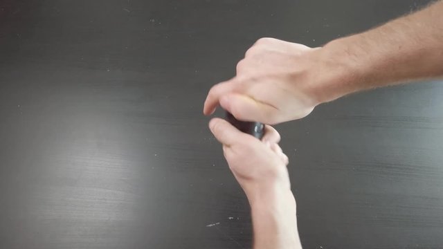 Caucasian male hands twisting a weed grinder to shred marijuana buds for legal or illegal drug use.