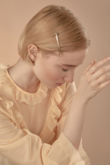 Close-up medium shot of a young blonde European girl with a lustrous hair-slide in her short...