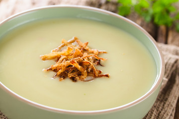 Fresh homemade cream of potato soup in bowl garnished with crispy onion strings (Selective Focus, Focus on the onion strings in the front)