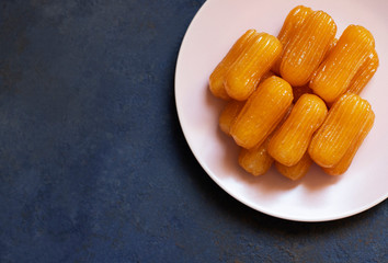Traditional dessert called tulumba. Turkish cuisine. Balkan cuisine. Levantine cuisine. On a blue background, served on a pink plate