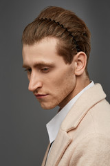 Cropped close-up shot of a young chestnut European man with a hairband in the form of a black wavy...