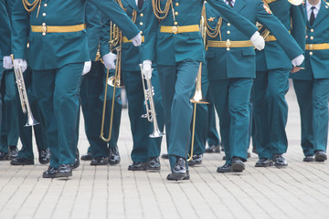 A wind instrument parade - people in green costumes walking on the street holding musical...