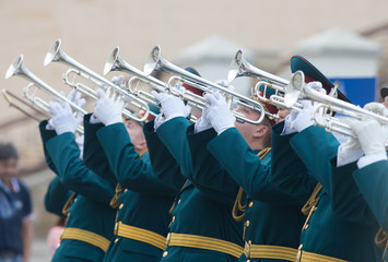 A wind instrument parade - men in green official costumes playing trumpets