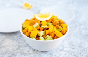 Pegan salad with mango, avocado and sweet potatoes, served with lemon water. Paleo diet. Pegan diet. Vegetarian food. Light background