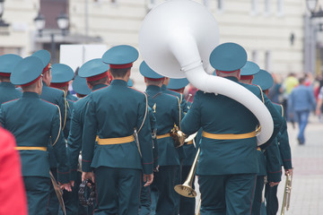 A wind instrument parade - people in green costumes walking on the street holding musical...