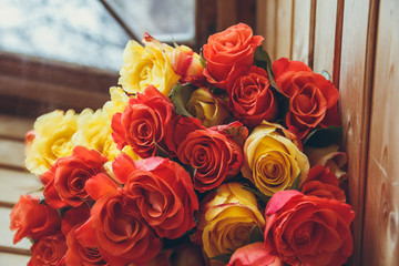 A beautiful bouquet of roses lies on a table by the window. Bouquet of flowers on the veranda. Yellow and red flowers on the table.