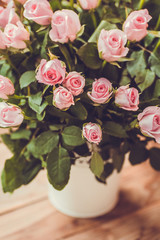 Gorgeous bouquet of flowers in a white pot. Pink and raspberry roses in a vase on the window.