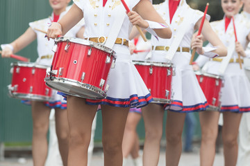 A wind instrument parade - women in small skirts playing red drums