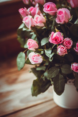Gorgeous bouquet of flowers in a white pot. Pink and raspberry roses in a vase on the window.