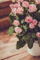Gorgeous bouquet of flowers in a white pot. Pink and raspberry roses in a vase on the window.