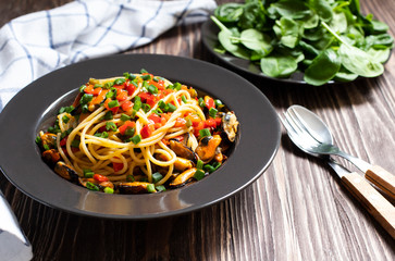 Traditional Italian seafood spaghetti pasta  with mussels served on a dark rustic wooden table with salad. Close-up view