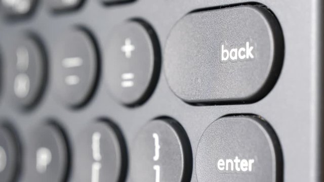 Closeup of finger pressing backspace button on the black computer keyboard. Technology