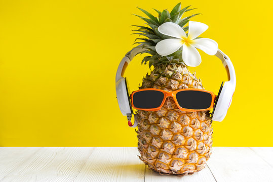Summer in the party.  Hipster Pineapple Fashion in sunglass and music bright beautiful color in holiday, Creative art fruit for tropical style on the beach vibes, yellwo background.  Fashion Summer 