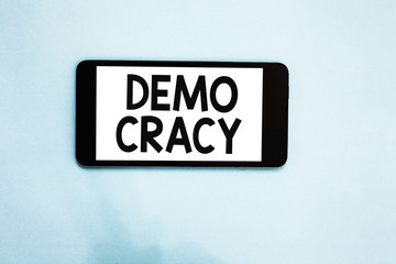Text sign showing Demo Cracy. Conceptual photo freedom of the people to express their feelings and beliefs Cell phone white screen over light blue background text messages apps