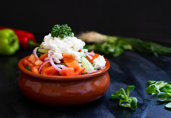 Traditional shopska salad with fresh vegetables and cheese. Traditional Balkan, Serbian, Bulgarian, Macedonian cuisine. Two plates of salad. Black background. Close-up view