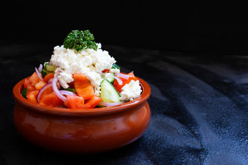 Traditional shopska salad with fresh vegetables and cheese. Traditional Balkan, Serbian, Bulgarian, Macedonian cuisine. Two plates of salad. Black background. Close-up view