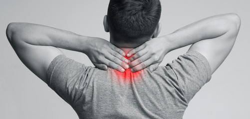 Young man massaging inflamed neck, back view