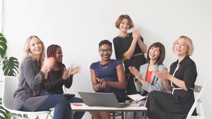 Portrait of multi-ethnic female group applauding their success while looking at camera.