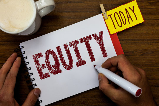 Writing note showing Equity. Business photo showcasing quality of being fair and impartial race free One hand Unity Man holding marker notebook pin reminder wooden table cup coffee