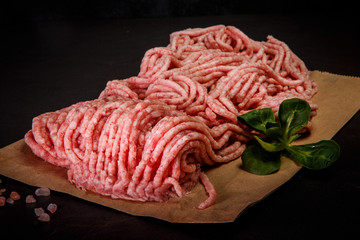 Obraz premium closeup raw minced meat on craft paper with spices and basil