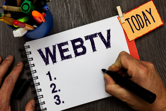 Handwriting text Webtv. Concept meaning Internet transmission programs produced both online and traditional Man holding marker notebook clothespin hold reminder cup markers wood table