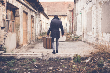 Fototapeta na wymiar Back view of man carrying suitcase and walking away.