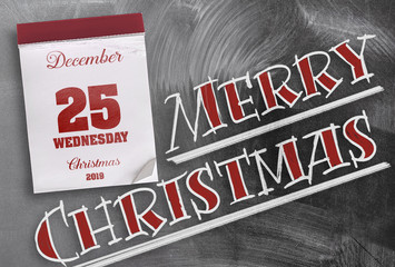 words Merry Christmas on chalkboard with tear-off calendar on December 25