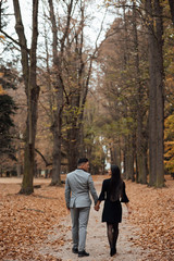 Lovers walking hand in hand in autumn park