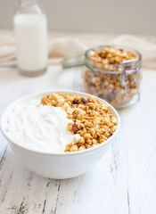 Fototapeta na wymiar Bowl of Homemade granola with Greek yogurt on a light background. Ingredients for a healthy breakfast - granola and milk. Close-up