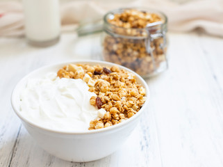 Bowl of Homemade granola with Greek yogurt on a light background. Ingredients for a healthy breakfast - granola and milk. Close-up