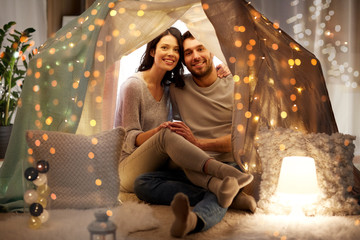 leisure, hygge and people concept - happy couple in kids tent at home © Syda Productions