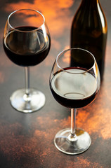 Red wine in a glass, close-up, selective focus. A bottle of red wine and two glasses on the table. Vertical
