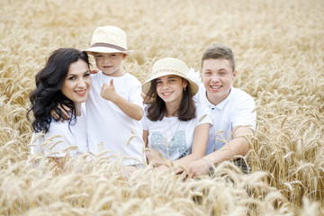 Happy family - brothers, sister and mom have fun on the wheat field. Summer vacation time