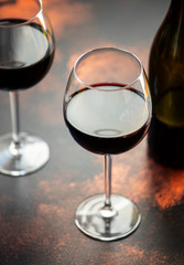 Red wine in a glass, close-up, selective focus. A bottle of red wine and two glasses on the table. Vertical