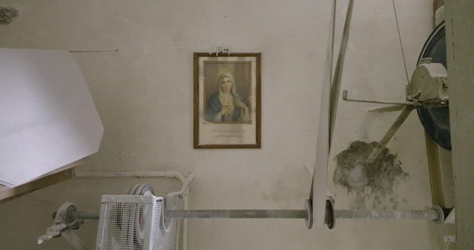 A detail fo the mechanism that make the flower in a old water mill of italy, with Virgin Mary on the wall