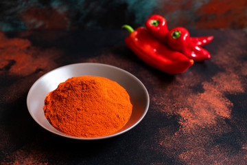 Paprika powder in a plate on a colorful oriental background. Bright colours. Selective focus. Space for text. Close-up