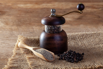 Black pepper and pepper grinder on wooden floor